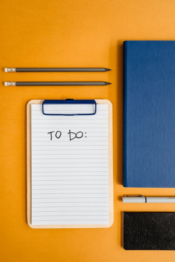 a-flatlay-of-stationery-and-writing-materials-7718650 Flat lay of stationery items including notebook, notepad, and pencils on an orange background for productivity themes.